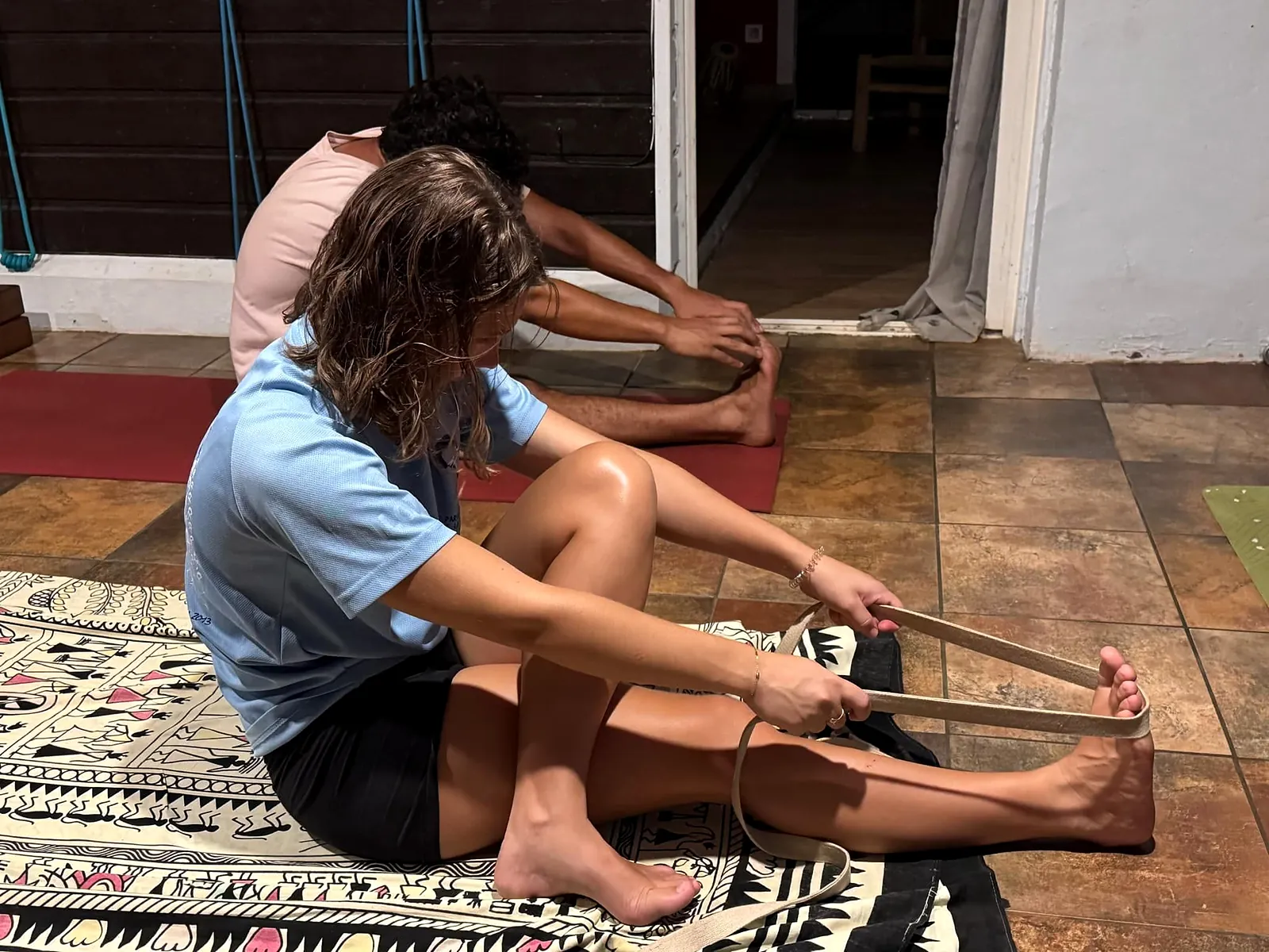 Élève assise en flexion avant avec une sangle, pendant un cours de yoga