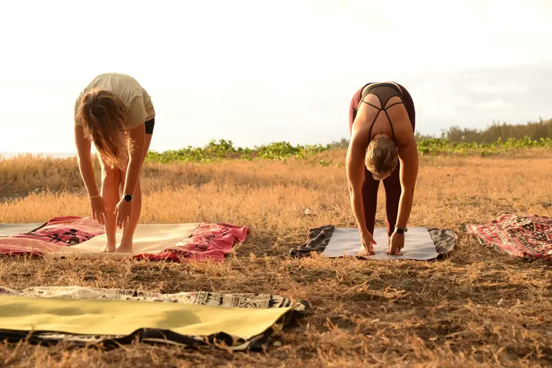Deux élèves en flexion avant au coucher du soleil, face à l'océan