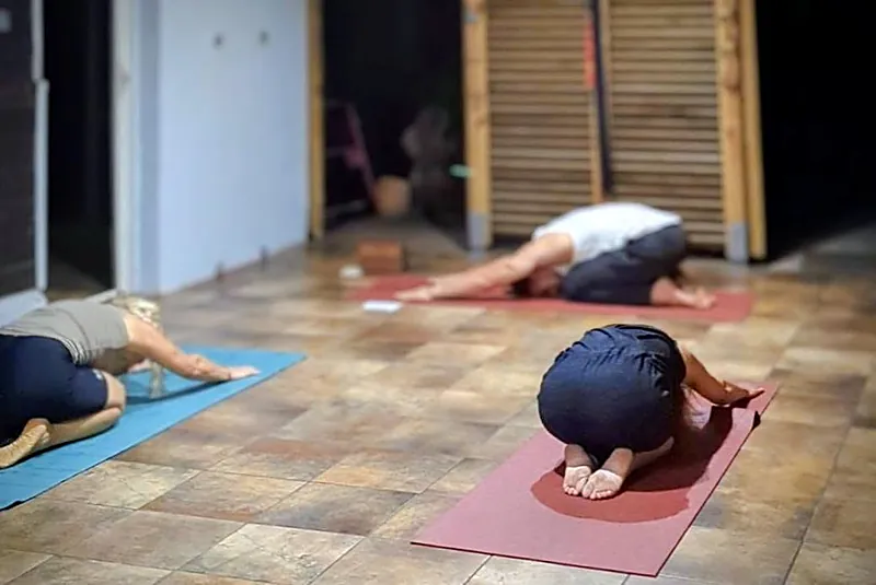 Élèves dans la posture de l'enfant pendant un cours de yoga en salle